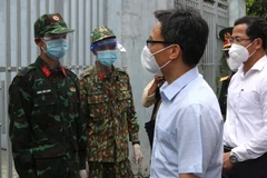 Phó Thủ tướng Vũ Đức Đam thăm hỏi chiến sĩ quân đội làm nhiệm vụ hỗ trợ người dân tại khu vực cách ly phong tỏa Phường Tân Chánh Hiệp, quận 12. (Ảnh: Xuân Tình/TTXVN)
