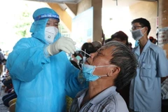 Các cán bộ Trung tâm Y tế lấy mẫu xét nghiệm cho tiểu thương. (Ảnh: Phạm Cường/TTXVN)