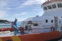 Phun khử khuẩn toàn bộ tàu SAR27-01 sau khi đưa thuyền viên người nước ngoài lên bờ đi cấp cứu. (Ảnh: Phan Sáu/TTXVN)