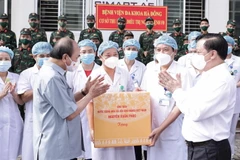 Chủ tịch nước Nguyễn Xuân Phúc tặng quà các nhân viên y tế làm việc cơ sở thu dung, điều trị bệnh nhân COVD-19 của Bệnh viện Đa khoa Hà Đông. (Ảnh: Thống Nhất/TTXVN)