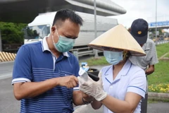 Nhân viên y tế hướng dẫn người đi từ Thành phố Hồ Chí Minh về Đồng Nai thực hiện khai báo y tế tại chốt kiểm soát trên Quốc lộ 51, đoạn giao với cao tốc Thành phố Hồ Chí Minh-Long Thành-Dầu Giây. (Ảnh: Lê Xuân/TTXVN)
