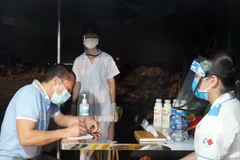 Lực lượng y tế tại chốt kiểm dịch chân cầu Yên Dũng nối tỉnh Bắc Ninh và Bắc Giang hỗ trợ người dân khai báo y tế. (Ảnh: Đinh Văn Nhiều/TTXVN)