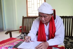 Cả sư Đổng Bạ biên tập các phong tục, nghi lễ truyền thống bằng tiếng Chăm. (Ảnh: Nguyễn Thành/TTXVN)