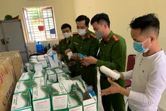 Lực lượng công an kiểm tra lô hàng khẩu trang vừa bị thu giữ. (Nguồn: TTXVN phát)