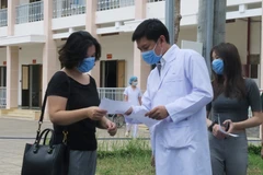 Bác sỹ Trần Chánh Xuân, Phó Giám đốc Bệnh viện dã chiến Củ Chi, trao giấy ra viện cho bệnh nhân số 75. (Ảnh: Đinh Hằng/TTXVN) 