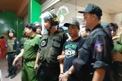 Cảnh sát dẫn giải một đối tượng đến bệnh viện khống chế người để đòi nợ. (Ảnh: Sỹ Tuyên/TTXVN)