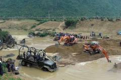 Các phương tiện xe, máy xúc đang tiến hành trục vớt cây gỗ sưa. (Nguồn: Đức Thọ-TTXVN)