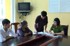 Đại úy Đặng Thị Thủy Hiền hướng dẫn các thủ tục hành chính cho người dân. (Ảnh: Phạm Kiên/TTXVN)