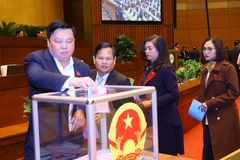 Đại biểu Quốc hội bỏ phiếu miễn nhiệm Chủ tịch nước Nguyễn Xuân Phúc. (Ảnh: Văn Điệp/TTXVN)