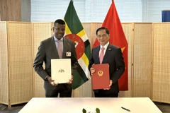 Bộ trưởng Ngoại giao Bùi Thanh Sơn và Bộ trưởng Ngoại giao, Ngoại thương, Thương mại và Năng lượng Cộng đồng Thịnh vượng Dominica Vince Henderson (đứng, bên trái) tại lễ ký. (Ảnh: Thanh Tuấn/TTXVN)