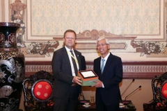 Phó Thị trưởng thứ nhất thành phố Leipzig Torsen Bonew (trái) trao tặng sản phẩm đồ sứ sản xuất tại Leipzig cho Phó Chủ tịch UBND thành phố Võ Văn Hoan. (Ảnh: Xuân Khu/TTXVN)