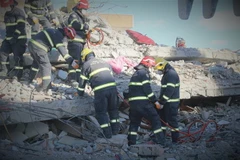 Các thành viên của đội dùng máy cắt chuyên dụng để loại bỏ các đoạn sắt thép xen kẽ trong những mảng bêtông lớn. (Ảnh: Trường Dụy/TTXVN)