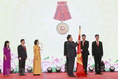 Chủ tịch Quốc hội Vương Đình Huệ gắn Huân chương Lao động hạng Nhì lên cờ truyền thống của Ban Công tác đại biểu. (Ảnh: Doãn Tấn/TTXVN)