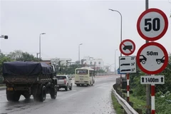 Cơ quan chức năng cắm bảng cảnh báo cầu yếu, giới hạn trọng tải và khoảng cách khi lưu thông qua cầu Trà Khúc. (Ảnh: Phạm Cường/TTXVN)