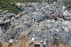 Lực lượng cứu hộ và tình nguyện viên tìm kiếm các nạn nhân và người sống sót mắc kẹt trong đống đổ nát sau động đất mạnh ở làng Besnia, gần thị trấn Harim, tỉnh Idlib, Syria, giáp giới Thổ Nhĩ Kỳ. (Ảnh: AFP/TTXVN)