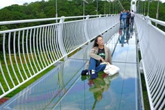 Một khách du lịch tạo dáng chụp hình 'sống ảo' trên cầu kính duy nhất ở Tây Nguyên. (Ảnh: Nguyễn Dũng/TTXVN)