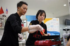 Đầu bếp Christine Ha (phải) và đầu bếp Tuyết Phạm - á quân MasterChef Việt Nam 2015 truyền cảm hứng nấu ăn cho các học viên. (Ảnh: Trần Lê Lâm/TTXVN)