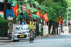 Người dân thư thái đạp xe qua những con phố rực đỏ cờ Tổ quốc trong ngày Quốc khánh. (Ảnh: Phạm Tuấn Anh/TTXVN)