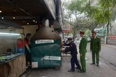 Lực lượng chức năng phường Giảng Võ (Ba Đình) xử lý cửa hàng kinh doanh ăn uống vi phạm vỉa hè trên địa bàn. (Ảnh: Mạnh Khánh/TTXVN)