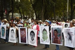 Thân nhân của 43 sinh viên mất tích và đại diện các tổ chức xã hội tham gia cuộc tuần hành ở Mexico City. (Nguồn: AFP/TTXVN)