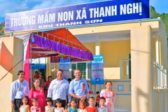 Các khách mời chụp hình lưu niệm với các bé trước ngôi trường mới. 