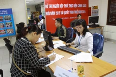 Người nộp thuế được giải đáp thắc mắc lĩnh vực thuế tại bàn hỗ trợ chính sách thuế - Cục Thuế Hà Nội. (Ảnh: Hoàng Hùng/TTXVN)