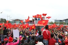 Các cầu thủ U23 Việt Nam trong rừng người hâm mộ vây quanh chào đón. (Ảnh: Quốc Khánh/TTXVN)