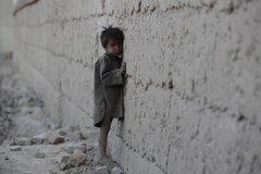 Một em bé Afghanistan đứng dựa vào bức tường khu vực đổ nát do xung đột ở ngoại ô Kabul tháng 10/2011. (Nguồn: AFP/TTXVN)