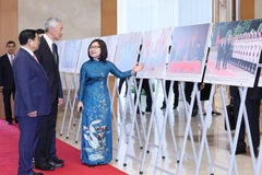 Phó Tổng Giám đốc TTXVN Đoàn Thị Tuyết Nhung giới thiệu với Thủ tướng Phạm Minh Chính và Thủ tướng Lý Hiển Long hình ảnh về quá trình hợp tác giữa Việt Nam và Singapore.