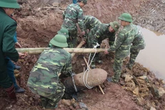Lực lượng công binh tiến hành trục vớt quả bom nằm sâu dưới lòng đất. (Ảnh: Mai Ngoan/TTXVN)