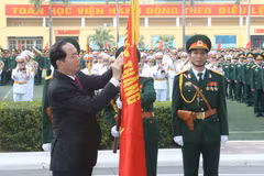 Chủ tịch nước Trần Đại Quang gắn Huân chương Độc lập hạng Nhì lên cờ truyền thống của Học viện. (Ảnh: Nhan Sáng/TTXVN)