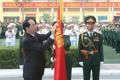 Chủ tịch nước Trần Đại Quang gắn Huân chương Độc lập hạng Nhì lên cờ truyền thống của Học viện. (Ảnh: Nhan Sáng/TTXVN)