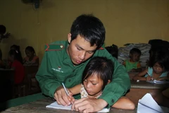 Dù là lớp học phổ cập xóa mù chữ, nhưng các em nhỏ luôn được những thầy giáo mang quân hàm xanh ở Đồn biên phòng Tuyên Bình chỉ bảo tận tình. (Ảnh: Trường Giang/TTXVN)