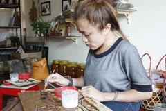 Võ Thị Thanh Thảo miệt mài hoàn thành một tác phẩm của mình. (Ảnh: Hồng Điệp/Vietnam+)