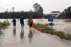 Lực lượng công an xã Hành Minh, huyện Nghĩa Hành túc trực kiểm tra các đường giao thông bị ngập lũ không cho người dân tự ý lưu thông. (Ảnh: Trần Lê Lâm/TTXVN)