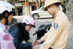 Lực lượng công an giao thông tăng cường xử phạt về vi phạm đội mũ bảo hiểm. (Ảnh: Vietnam+).