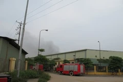 Lực lượng Phòng cháy chữa cháy vẫn đang túc trực để đề phòng đám cháy lớn vẫn âm ỉ và có khả năng lây lan. (Ảnh: Mạnh Hùng/Vietnam+).