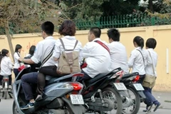 Học sinh đi xe máy dàn hàng ngang, không đội mũ bảo hiểm. (Ảnh: Văn Điệp/TTXVN)