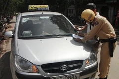 Xe taxi vi phạm bị Cảnh sát giao thông xử phạt trước cổng bệnh viện Việt Đức. (Ảnh: Việt Hùng/Vietnam+)