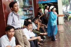 Phụ huynh ngồi vỉa hè chờ thí sinh thi tốt nghiệp. (Ảnh: PV/Vietnam+)