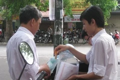 Thí sinh và phụ huynh đang chuẩn bị các giấy tờ và dụng cụ để dự thi. (Ảnh: PV/Vietnam+)