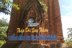 Tháp Đôi bị khoan vào tường gạch, bắt vít sắt thép để gắn biển giới thiệu tên di tích. (Ảnh: TTXVN)