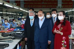 Chủ tịch nước Nguyễn Xuân Phúc thăm Công ty TNHH sản xuất dịch vụ thương mại sản phẩm da LADODA, do ông Đinh Quang Bào, 83 tuổi là đại diện pháp luật. (Ảnh: Thống Nhất/TTXVN)