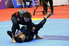 Vận động viên Nguyễn Đình Tuấn (Việt Nam-đỏ) thi đấu với vận động viên Khoirudin Mustakim (Indonesia-xanh). (Ảnh: Quang Quyết/TTXVN)