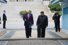 Tổng thống Mỹ Donald Trump (trái) và nhà lãnh đạo Triều Tiên Kim Jong-un bước chân qua đường ranh giới phân chia hai miền Triều Tiên tại DMZ, sang phần lãnh thổ của Triều Tiên chiều 30/6. (Nguồn: Yonhap/TTXVN)