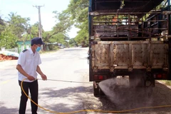 Lực lượng chức năng phun thuốc sát trùng phương tiện vận chuyển lợn qua địa bàn. (Ảnh: Công Thử/TTXVN)