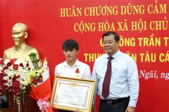 Phó chủ tịch UBND tỉnh Quảng Ngãi Nguyễn Tăng Bính trao Huân chương Dũng cảm cho ngư dân Trần Thanh Ron. (Ảnh: Phước Ngọc/TTXVN)