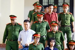 Bị cáo Phan Sào Nam (áo trắng) cùng các bị cáo được cơ quan chức năng dẫn giải ra tòa. (Ảnh: Trung Kiên/TTXVN)