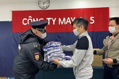 Đại diện Công an Thành Phố Plavsk nhận khẩu trang từ Công ty may 9-5. (Ảnh: Duy Trinh/TTXVN)