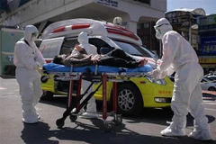 Nhân viên y tế chuyển bệnh nhân nghi nhiễm COVID-19 tới bệnh viện tại Daegu, Hàn Quốc, ngày 12/3/2020. (Ảnh: AFP/TTXVN)